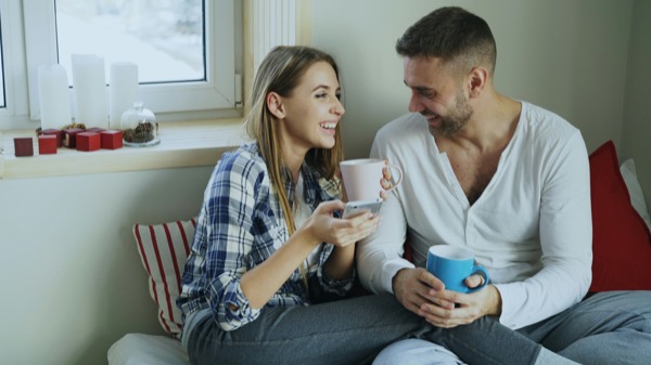ソファでコーヒーを飲みながら話すカップル