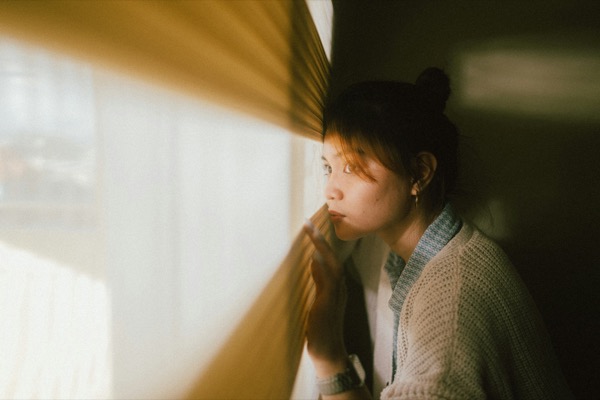 やわらかな日差しの窓辺で物思いにふける女性