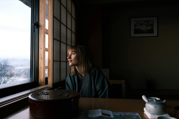 和室の窓辺で朝の景色を眺める女性